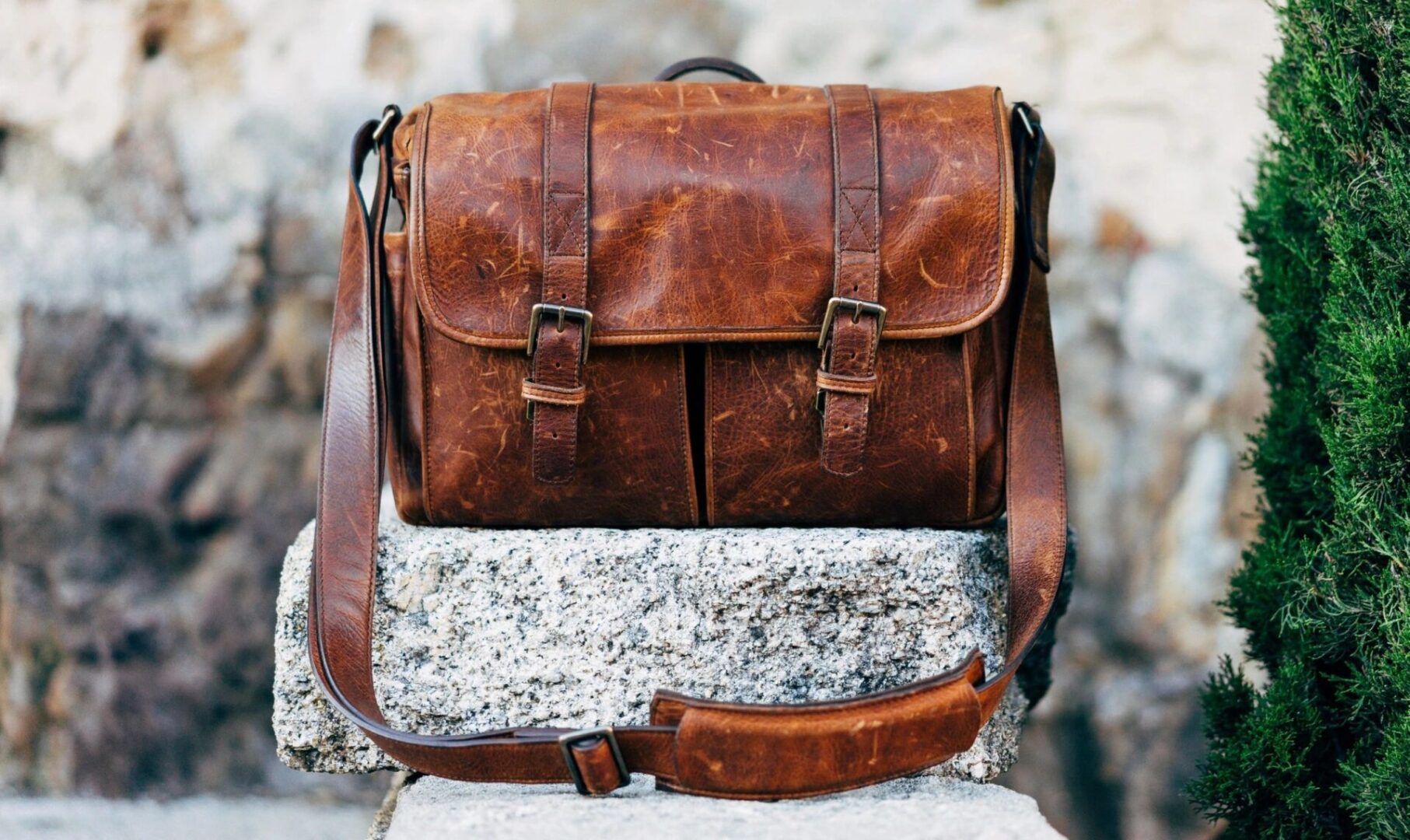 A brown leather bag sitting on top of a rock.